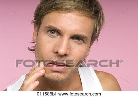 Stock Image - young man checking himself in a mirror. Fotosearch