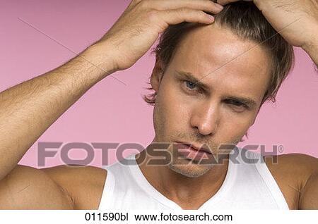 Stock Image - young man checking his hair in a mirror. Fotosearch