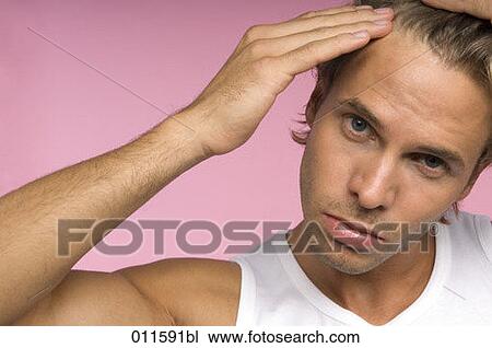 Stock Image - young man checking his hair in the mirror. Fotosearch