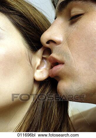 Stock Image - young man kissing woman´s ear. Fotosearch
