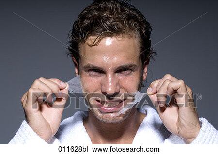 Stock Image - young man peeling off his face mask. Fotosearch