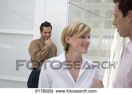 young office worker smiling behind the back of woman engaged in conversation with colleague View Large Photo Image Stock Image - young office worker smiling behind the back of woman engaged in conversation with colleague. Fotosearch