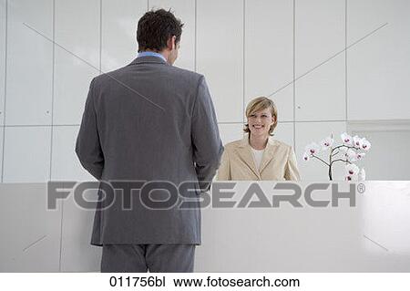 Stock Image - young receptionist welcoming businessman. Fotosearch