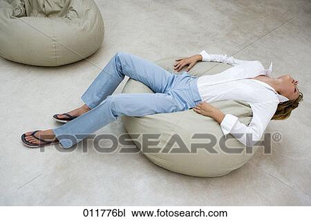 Stock Image - young woman sitting comfortably on bean bag. Fotosearch