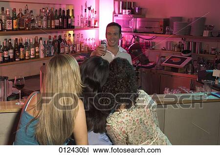 bartender photographing three women with camera phone View Large Photo Image Stock Image - bartender photographing three women with camera phone. Fotosearch