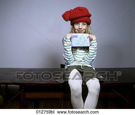 Stock Image - blonde girl in winter clothes holding letter for Santa Claus. Fotosearch
