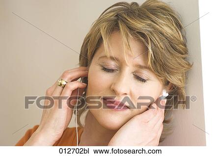close-up of mature woman leaning against wall and listening to music View Large Photo Image Stock Image - close-up of mature woman leaning against wall and listening to music. Fotosearch