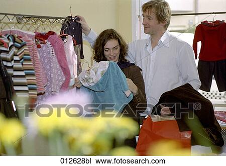 Stock Image - couple buying clothes for baby. Fotosearch