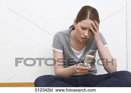 Stock Image - desperate teenager looking at display of her cellphone. Fotosearch