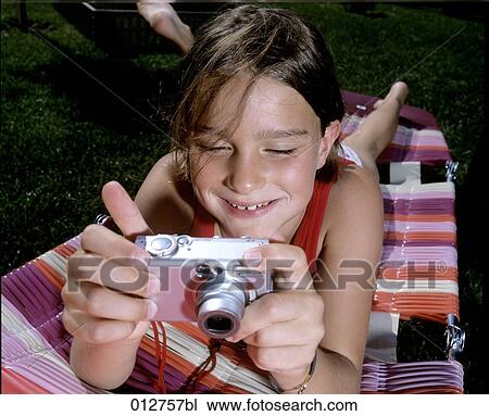 girl on sunlounger looking at display of digital camera View Large Photo Image Stock Image - girl on sunlounger looking at display of digital camera. Fotosearch