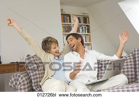 joyous couple sitting on couch with computer View Large Photo Image Stock Image - joyous couple sitting on couch with computer. Fotosearch