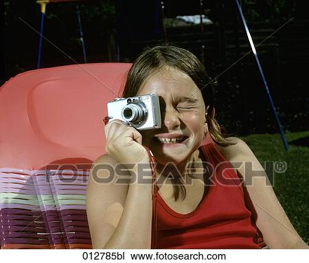 Stock Image - laughing girl having fun with digital camera. Fotosearch
