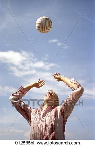 Stock Image - low angle view of young man playing volleyball. Fotosearch