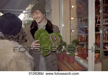 man showing his girlfriend flower arrangement with the shape of a heart View Large Photo Image Stock Image - man showing his girlfriend flower arrangement with the shape of a heart. Fotosearch