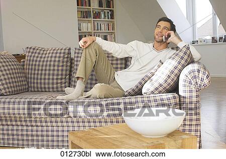 man sitting relaxed on his sofa talking on cellphone View Large Photo Image Stock Image - man sitting relaxed on his sofa talking on cellphone. Fotosearch