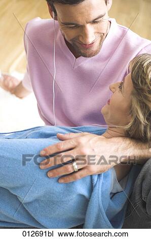 Stock Image - mature couple in tender embrace while listening to music. Fotosearch