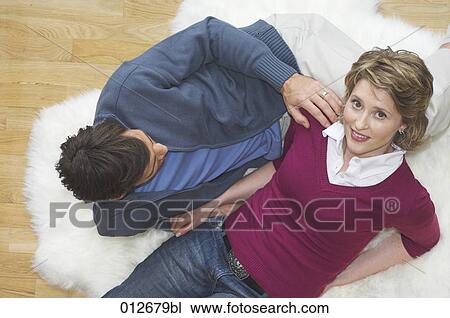 Stock Image - mature couple sitting on the floor man touching woman´s shoulder. Fotosearch