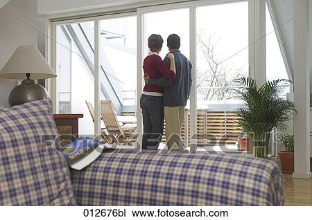 mature couple standing in living room looking out of the window View Large Photo Image Stock Image - mature couple standing in living room looking out of the window. Fotosearch