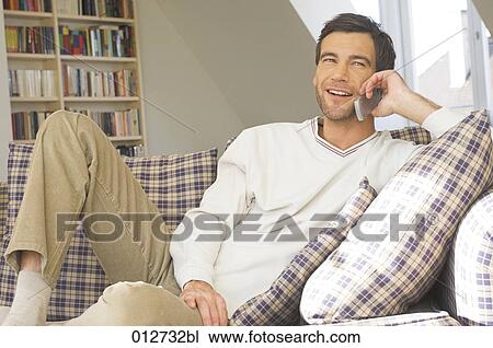 mature man listening to mobile phone while sitting on couch View Large Photo Image Stock Image - mature man listening to mobile phone while sitting on couch. Fotosearch