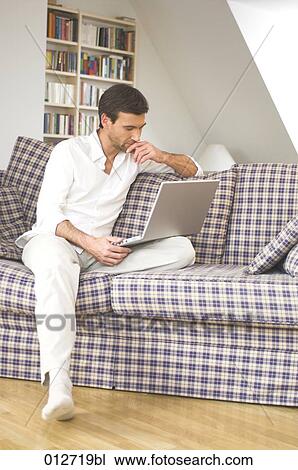 mature man sitting on couch looking at screen of his computer View Large Photo Image Stock Image - mature man sitting on couch looking at screen of his computer . Fotosearch