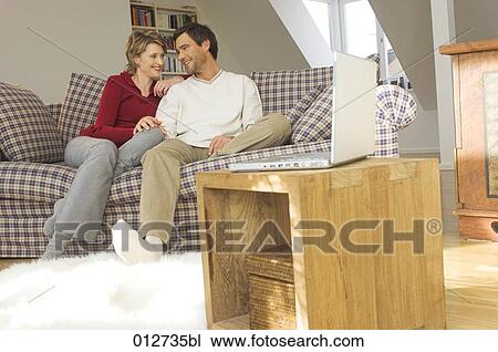 middle age couple relaxing on couch in living room View Large Photo Image Stock Image - middle age couple relaxing on couch in living room. Fotosearch