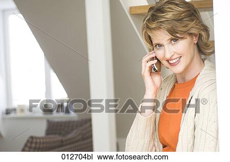middle aged woman having a conversation on her cellphone at home View Large Photo Image Stock Image - middle aged woman having a conversation on her cellphone at home. Fotosearch
