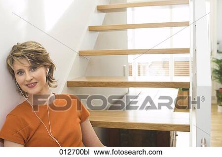 portrait of mature woman sitting by stairs wearing earphones View Large Photo Image Stock Image - portrait of mature woman sitting by stairs wearing earphones. Fotosearch