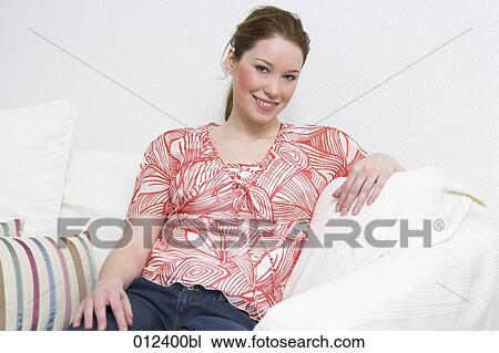 Stock Image - portrait of red haired teenage girl sitting comfortably on sofa. Fotosearch