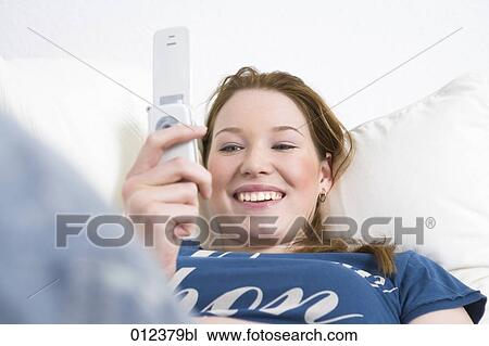 portrait of teenage girl smiling brightly while looking at display of her mobile View Large Photo Image Stock Image - portrait of teenage girl smiling brightly while looking at display of her mobile. Fotosearch