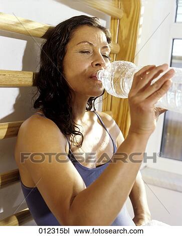 Stock Image - portrait of woman in gym drinking some water. Fotosearch