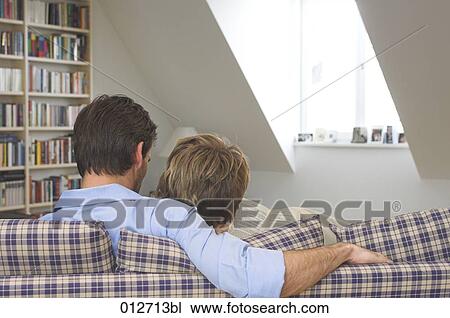 rear view of couple sitting on couch sharing a book View Large Photo Image Stock Image - rear view of couple sitting on couch sharing a book. Fotosearch
