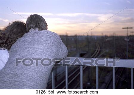 rear view of couple standing on bridge looking into the sunset View Large Photo Image Stock Image - rear view of couple standing on bridge looking into the sunset. Fotosearch