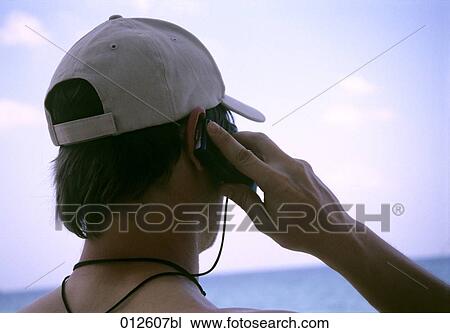 rear view of young man using mobile phone on tropical beach View Large Photo Image Stock Image - rear view of young man using mobile phone on tropical beach. Fotosearch