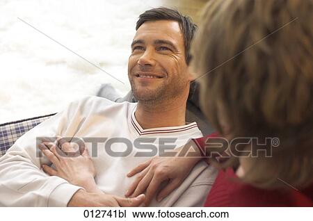 smiling man lying on sofa with woman in foreground View Large Photo Image Stock Image - smiling man lying on sofa with woman in foreground. Fotosearch
