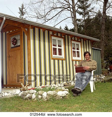 smiling man sitting in front of little hut holding radio on his lap View Large Photo Image Stock Image - smiling man sitting in front of little hut holding radio on his lap. Fotosearch