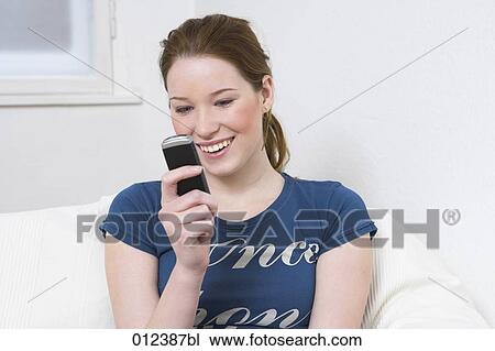 Stock Image - smiling teenager checking mobile for text messages. Fotosearch