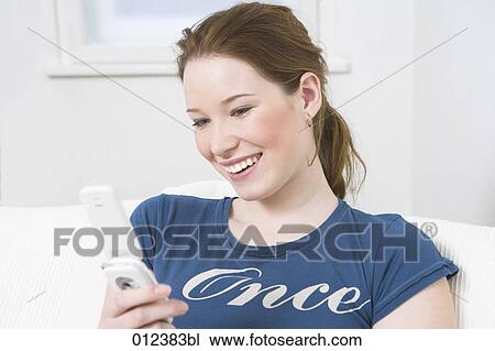 Stock Image - smiling woman looking at display of her cellphone. Fotosearch