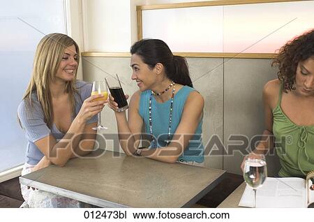 two female friends toasting to each other in cafe View Large Photo Image Stock Image - two female friends toasting to each other in cafe. Fotosearch