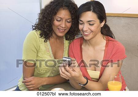 Stock Image - two friends looking at display of mobile phone. Fotosearch