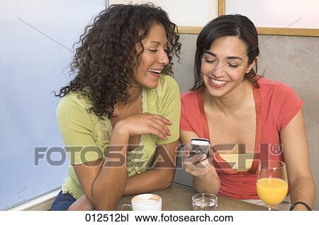 two young woman looking at display of mobile phone View Large Photo Image Stock Image - two young woman looking at display of mobile phone. Fotosearch