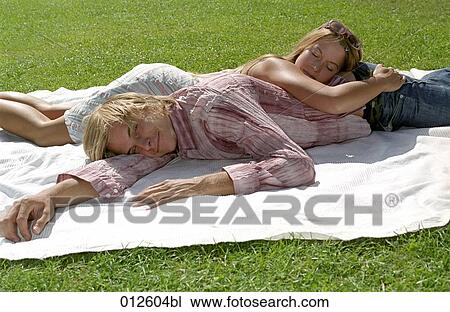 young couple dozing on towel in the park View Large Photo Image Stock Image - young couple dozing on towel in the park. Fotosearch