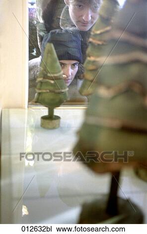 young couple looking through shop window with little christmas trees on display View Large Photo Image Stock Image - young couple looking through shop window with little christmas trees on display. Fotosearch