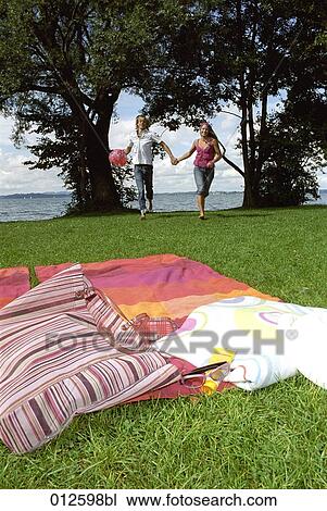 young couple running to take a rest on towel in the grass View Large Photo Image Stock Image - young couple running to take a rest on towel in the grass. Fotosearch