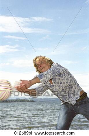 young man standing at lakeside trying to pass volleyball View Large Photo Image Stock Image - young man standing at lakeside trying to pass volleyball. Fotosearch