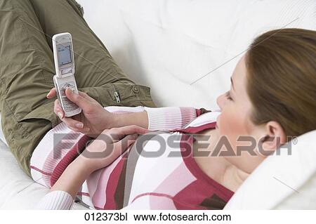 Stock Image - young woman checking her cellular phone for new text messages. Fotosearch
