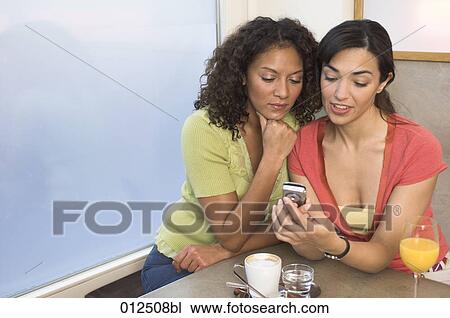 young woman explaining cellphone to her friend View Large Photo Image Stock Image - young woman explaining cellphone to her friend. Fotosearch