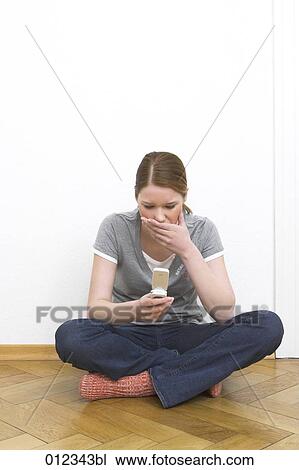 Stock Image - young woman shocked by news on her mobile phone. Fotosearch
