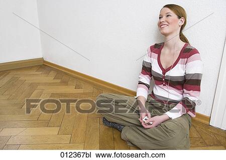 young woman sitting on floor and listening to music View Large Photo Image Stock Image - young woman sitting on floor and listening to music. Fotosearch