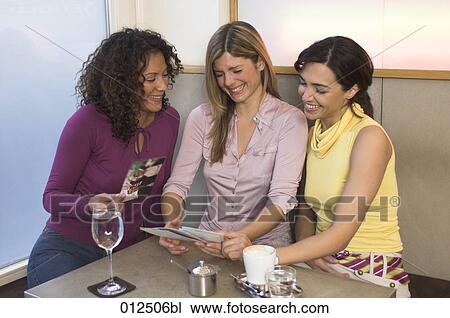young women having fun looking at photographs in restaurant View Large Photo Image Stock Image - young women having fun looking at photographs in restaurant. Fotosearch