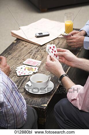 Stock Image - close-up of three businessmen playing cards. Fotosearch